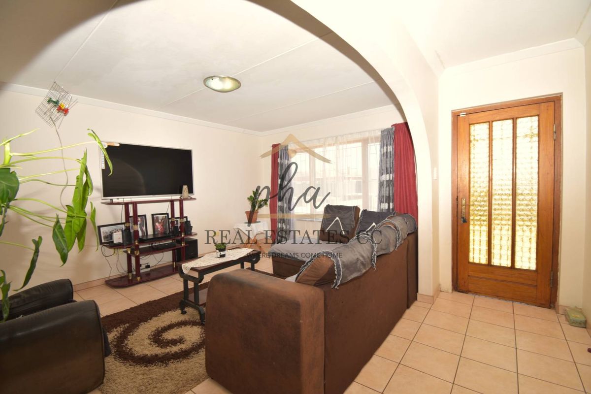 A living room featuring tiled flooring, an arched entryway, and a wooden front door with glass panels.
