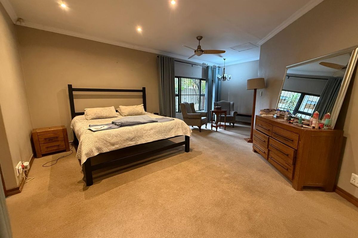 Spacious bedroom featuring recessed ceiling lighting, a ceiling fan, and large windows with security bars, offering a comfortable and functional living space.