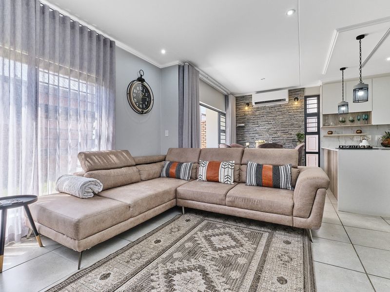 Modern open-plan living area featuring tiled floors, a stone-clad feature wall, split-system air conditioning, and a contemporary kitchen with built-in cabinetry and gas hob.