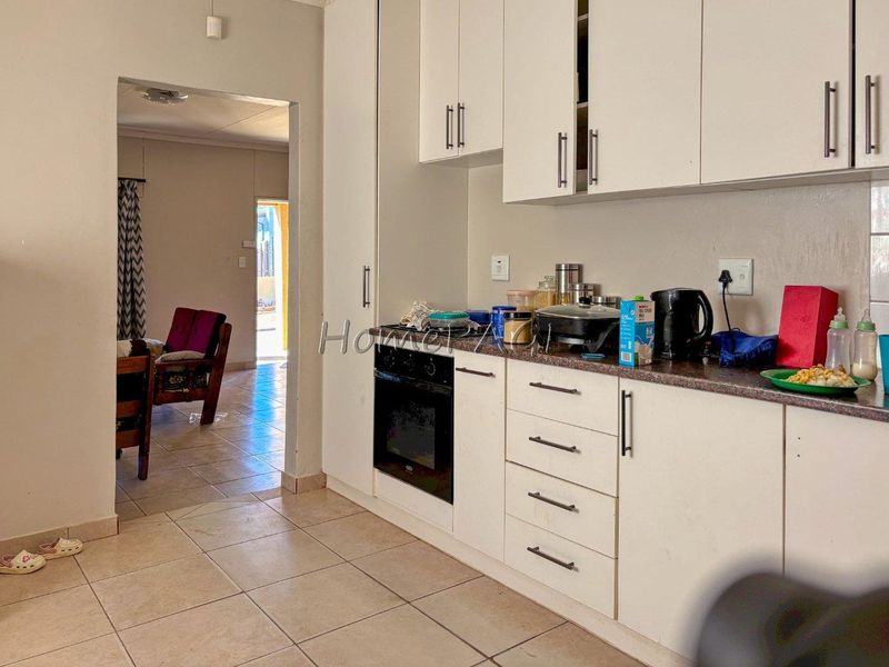 A functional kitchen featuring white built-in cabinetry, a built-in oven, and tiled flooring, providing a practical workspace for daily meal preparation.