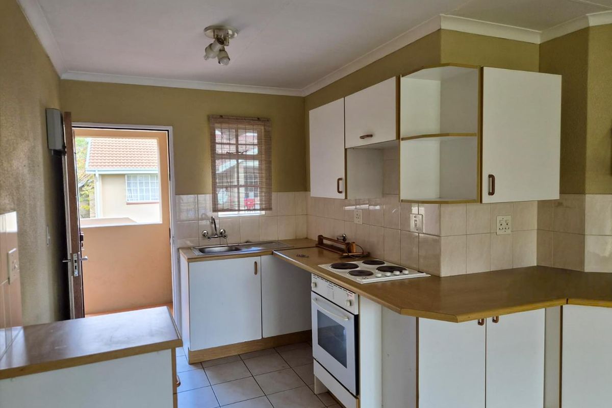 A functional kitchen featuring white cabinetry, laminate countertops, a built-in oven and hob, and direct access to an outdoor balcony area.