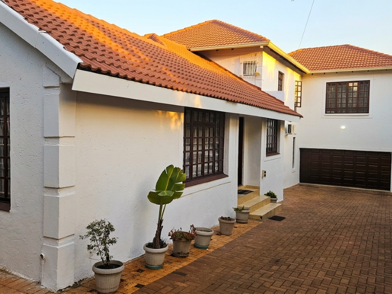 Front elevation of a double-story house featuring a terracotta tiled roof, paved driveway, and integrated garage.