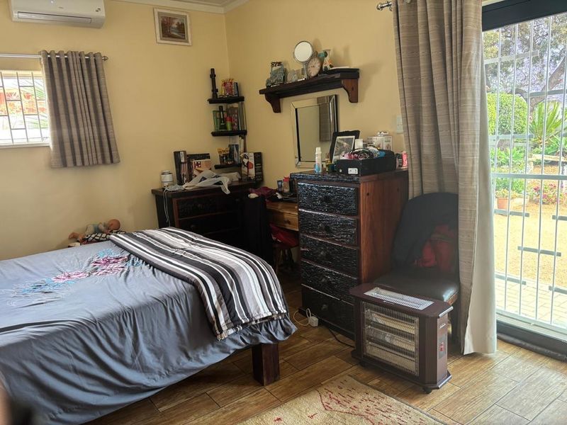 A bedroom featuring tiled flooring, a split-system air conditioner, and a sliding glass door providing direct access to the garden.