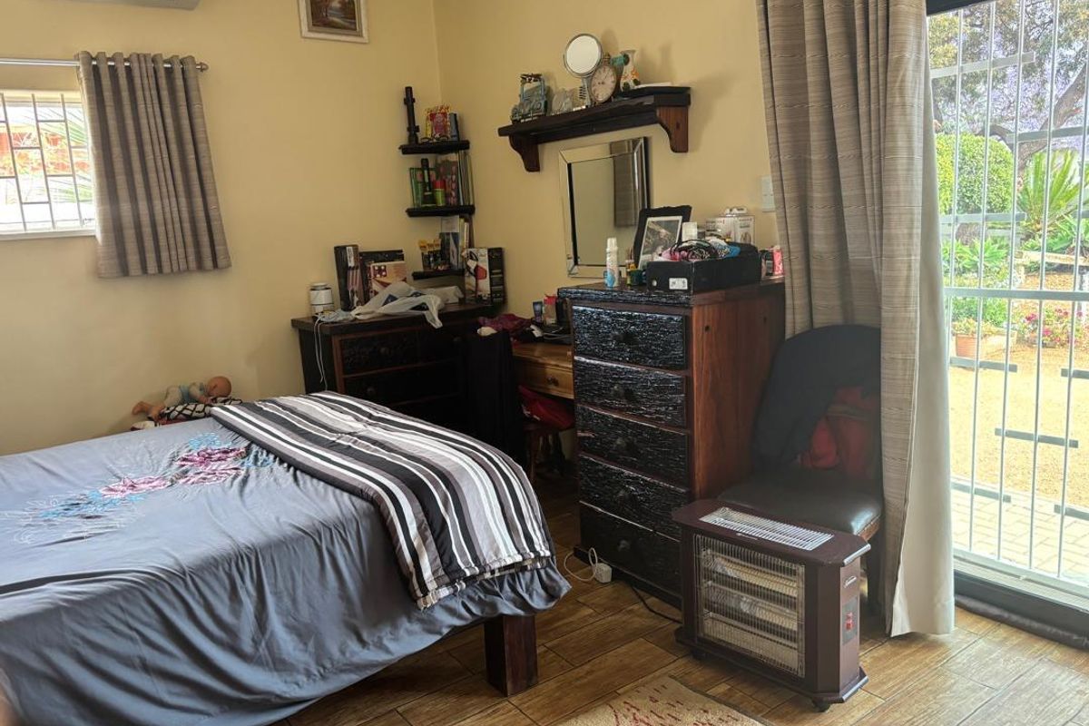 A bedroom featuring tiled flooring, a split-system air conditioner, and a sliding glass door providing direct access to the garden.