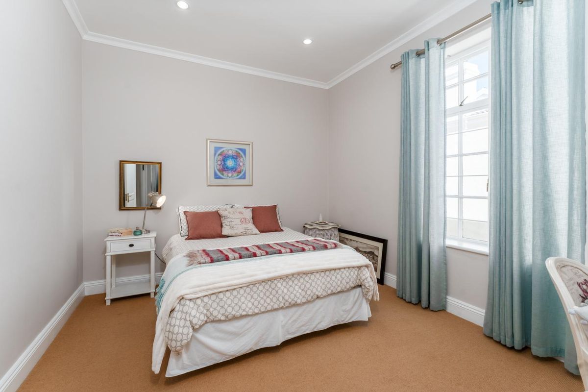 A well-maintained bedroom featuring neutral wall tones, recessed downlighting, coving, and a large multi-pane window that provides ample natural light.