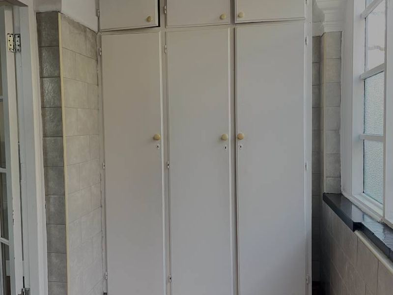 A functional hallway area featuring floor-to-ceiling built-in storage cabinetry, tiled wall finishes, and a window providing natural light.