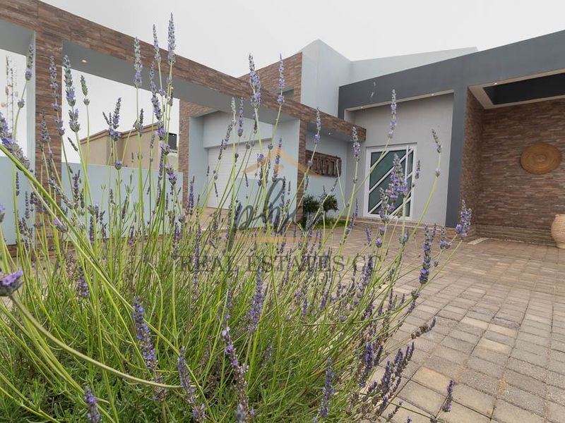 Modern front facade featuring stone cladding, paved driveway, and integrated garage, showcasing a contemporary architectural design.