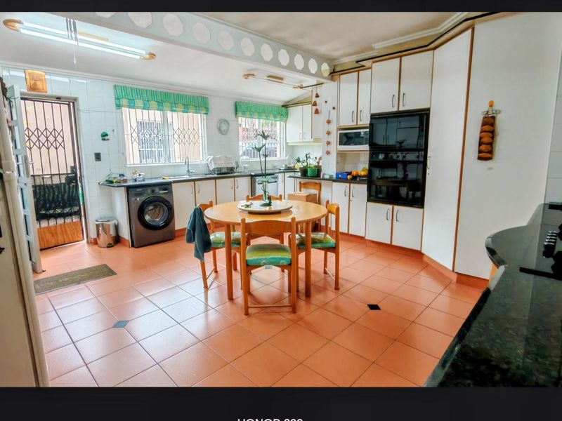 Spacious kitchen featuring built-in cabinetry, double wall oven, integrated microwave, and tiled flooring with direct access to an exterior security door.