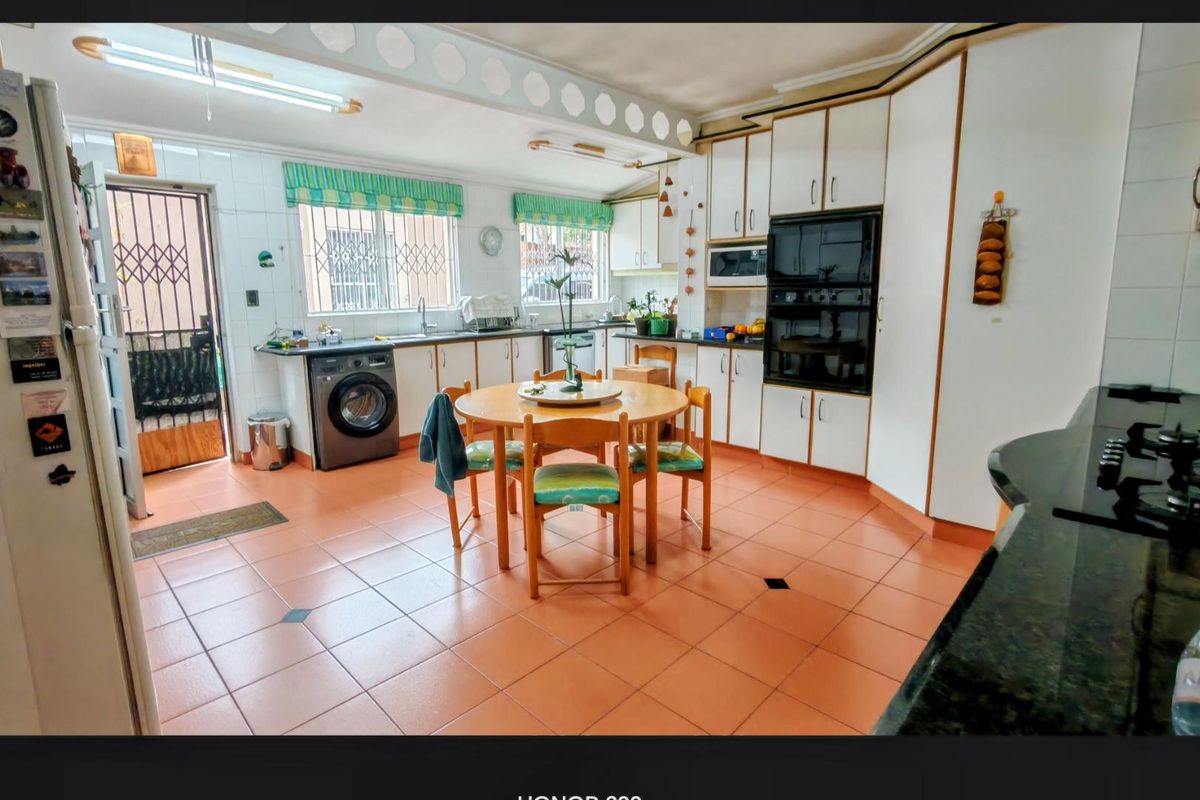 Spacious kitchen featuring built-in cabinetry, double wall oven, integrated microwave, and tiled flooring with direct access to an exterior security door.