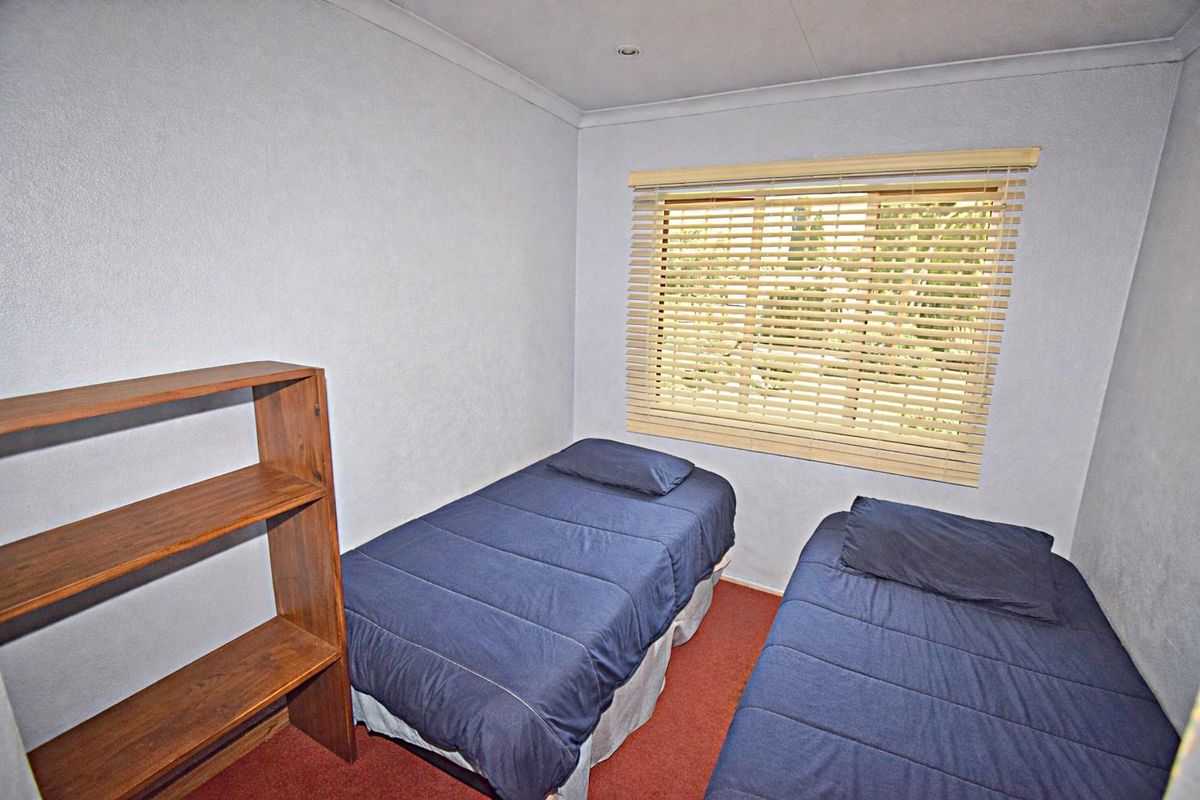 A compact bedroom featuring carpeted flooring, recessed ceiling lighting, and a window fitted with horizontal blinds.