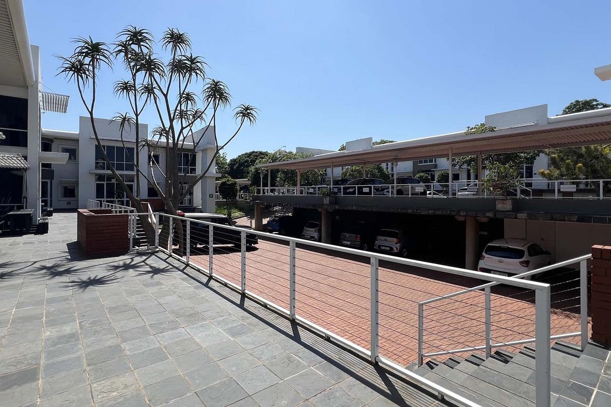 Exterior view of a modern business complex featuring paved walkways, multi-level covered parking structures, and clean architectural lines.