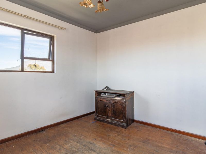 A vacant bedroom featuring original timber flooring, a casement window, and a painted ceiling, offering a blank canvas for renovation and modernization.