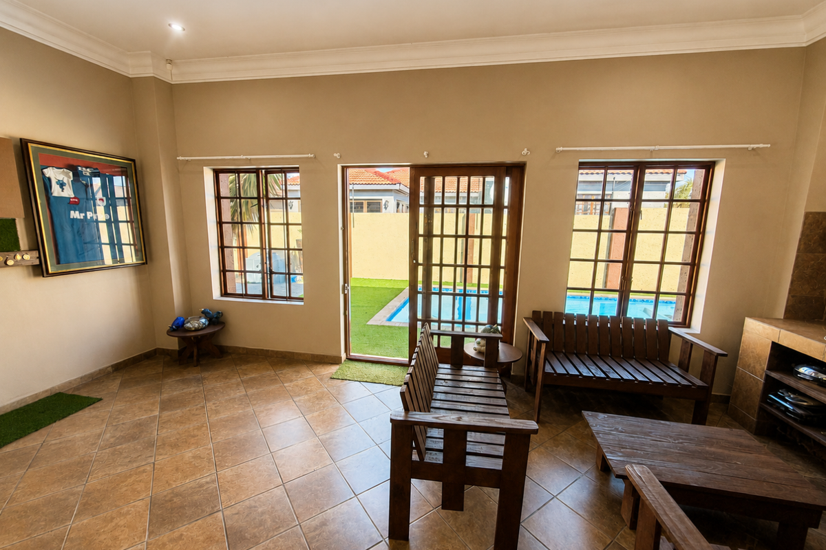 Spacious living area featuring tiled floors, recessed lighting, and direct access to an outdoor patio and swimming pool area through sliding glass doors.