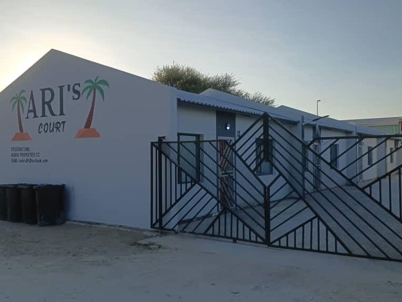 Front exterior view of Tari's Court featuring a painted masonry facade, prominent signage, and a secure metal entrance gate.