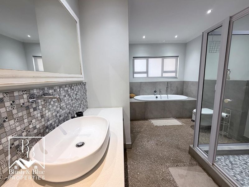 Modern bathroom featuring a vessel sink, wall-mounted faucet, built-in bathtub, and a glass-enclosed shower with contemporary tile finishes.