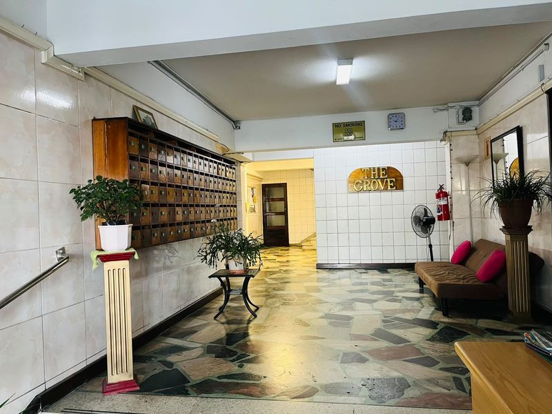 Communal apartment building entrance lobby featuring tiled flooring, wall-mounted mailboxes, and basic building signage.