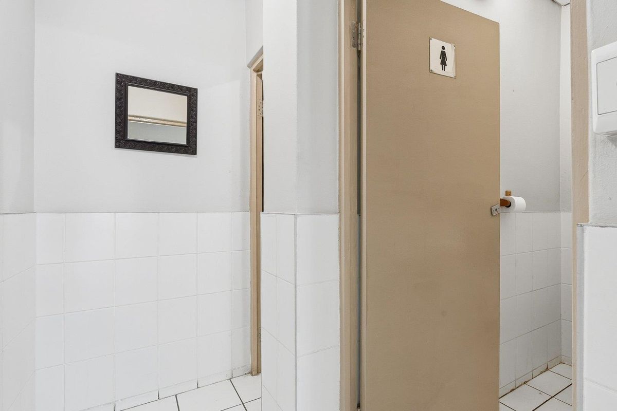 A functional restroom area featuring tiled walls and flooring, with a dedicated door for privacy.