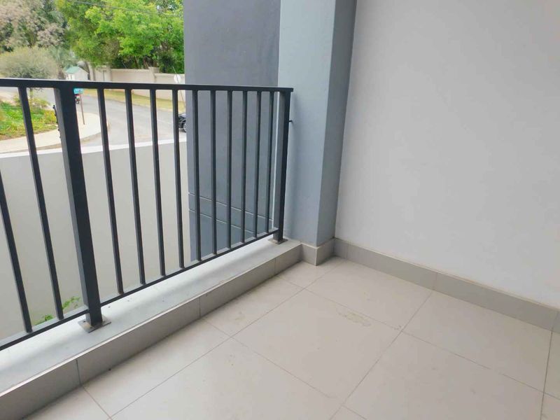 A clean, empty balcony featuring tiled flooring and a secure metal balustrade, offering an open outdoor space.