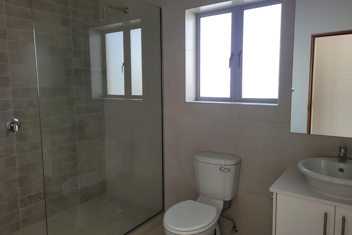 Modern bathroom featuring a glass-enclosed walk-in shower, a white vanity with a vessel sink, and a standard toilet.