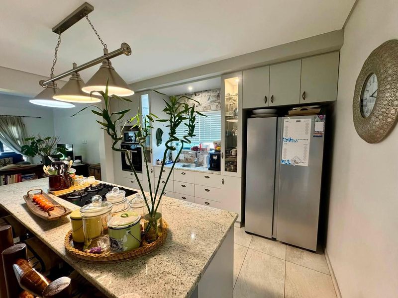Modern kitchen featuring granite countertops, built-in oven, gas hob, ample cabinetry, and stylish pendant lighting, seamlessly integrated into the open-plan living space.