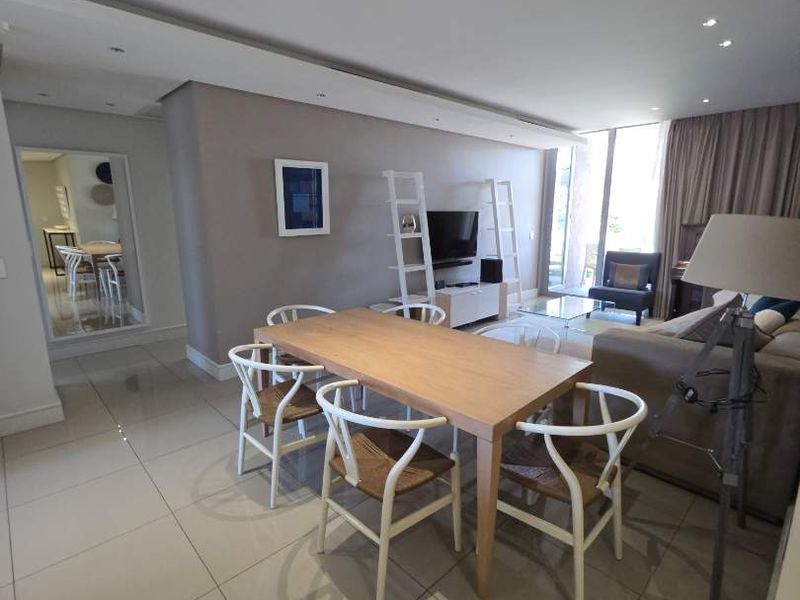 Spacious open-plan living and dining area featuring modern porcelain floor tiles, recessed downlighting, and large sliding glass doors leading to an outdoor space.