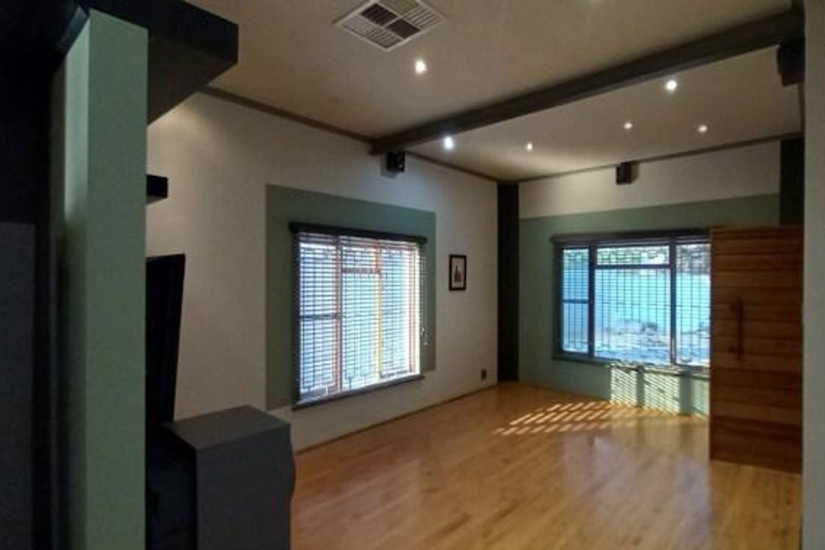 Spacious living room featuring hardwood flooring, recessed ceiling lighting, and large windows with fitted blinds.