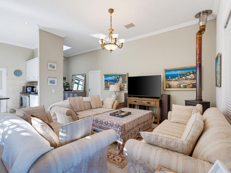 Spacious open-plan living area featuring a cozy fireplace, high ceilings with skylights, and an integrated kitchen space.
