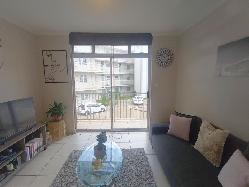 A living room featuring tiled flooring and a large sliding glass door that provides access to an outdoor balcony area.