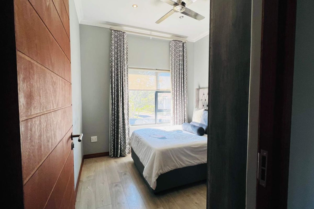 A well-maintained bedroom featuring laminate flooring, a ceiling fan, and recessed lighting, offering a comfortable and functional living space.