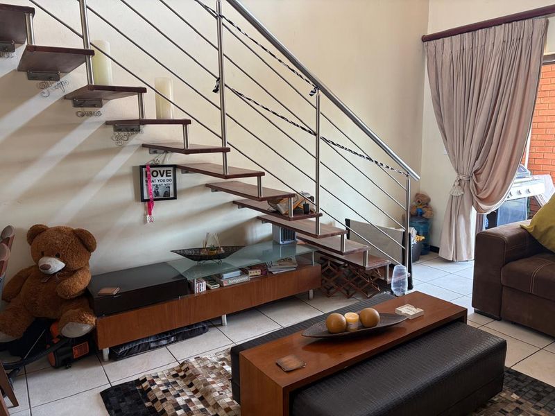 Living area featuring a modern floating staircase with a stainless steel balustrade and tiled flooring.