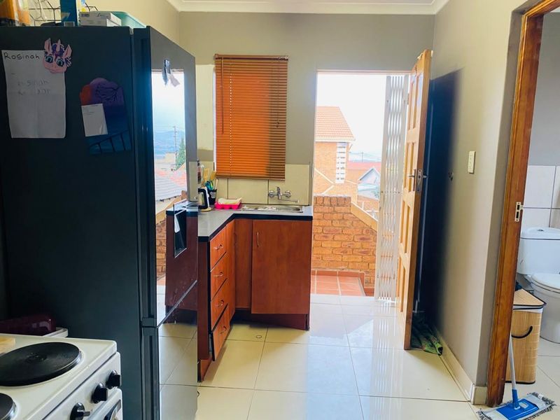 Compact kitchen featuring wooden cabinetry, laminate countertops, and tiled flooring, with direct access to an outdoor balcony area.