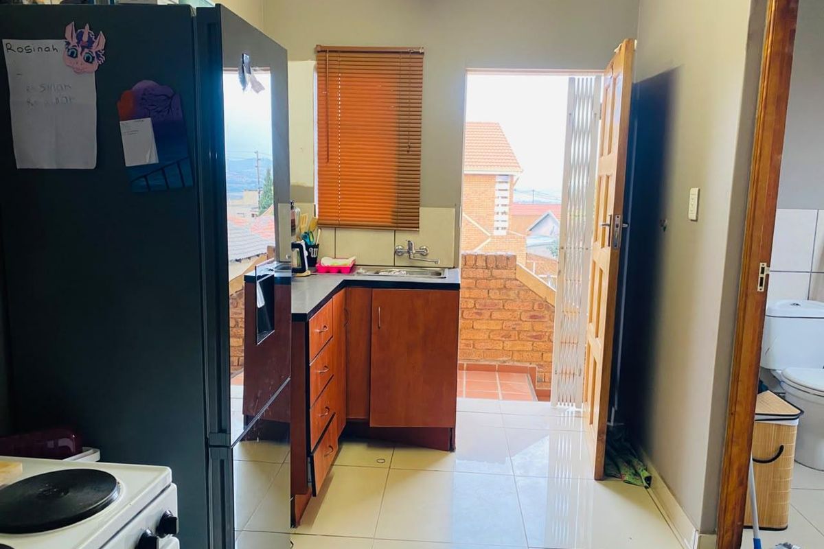 Compact kitchen featuring wooden cabinetry, laminate countertops, and tiled flooring, with direct access to an outdoor balcony area.
