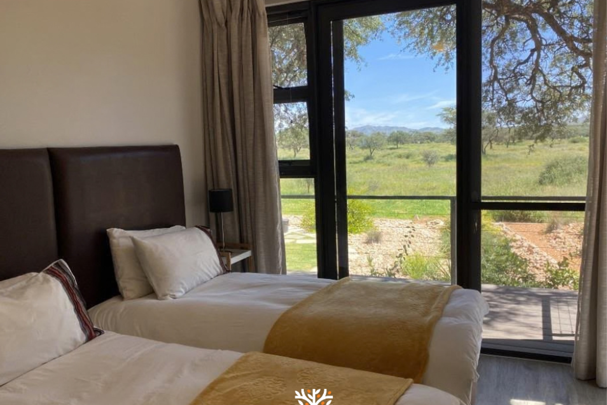A bright bedroom featuring large glass sliding doors that open to a scenic outdoor view, complemented by modern laminate flooring and neutral finishes.
