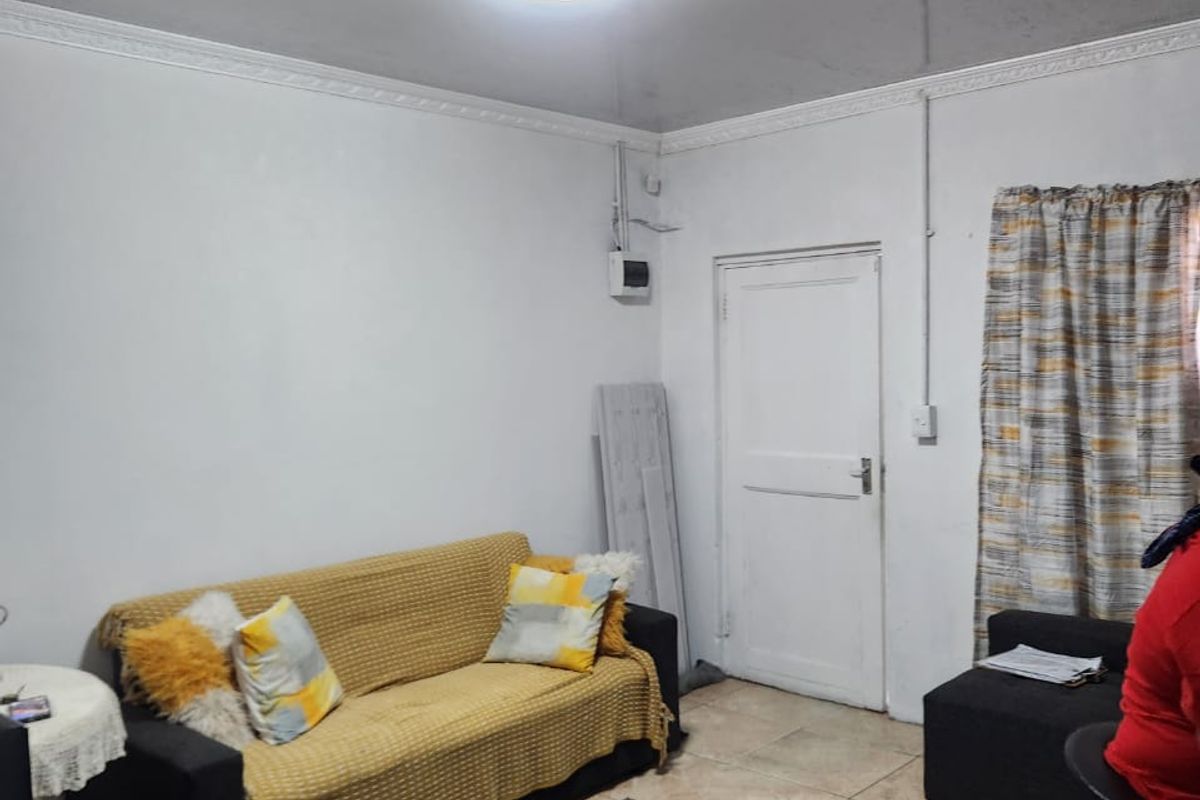 A functional living room featuring tiled flooring, ceiling cornice detailing, and a central flush mount light fixture.