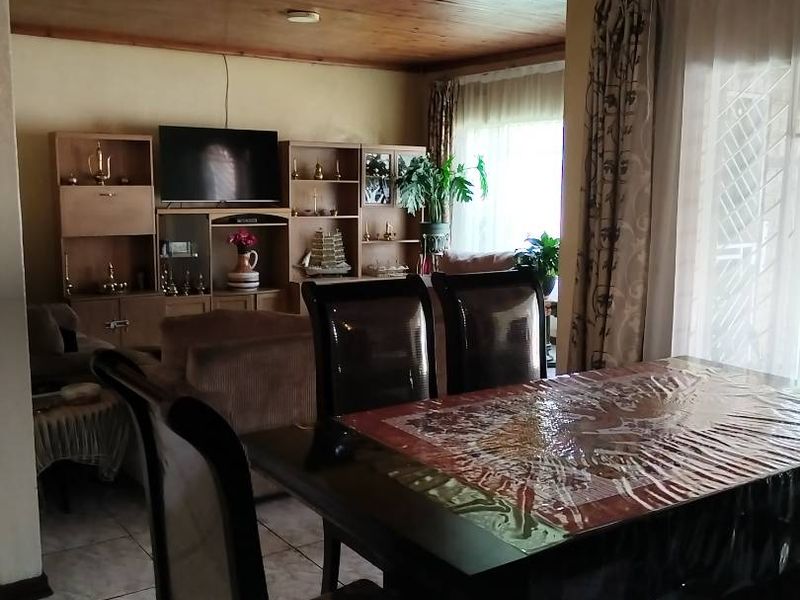 Open-plan living and dining area featuring a warm timber ceiling and tiled flooring, with direct access to the outdoors via a sliding door.