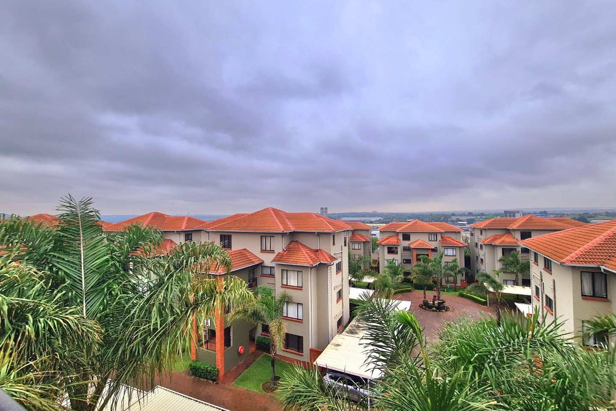 Elevated aerial view of a residential apartment complex featuring terracotta tiled roofs, paved driveways, and landscaped grounds.