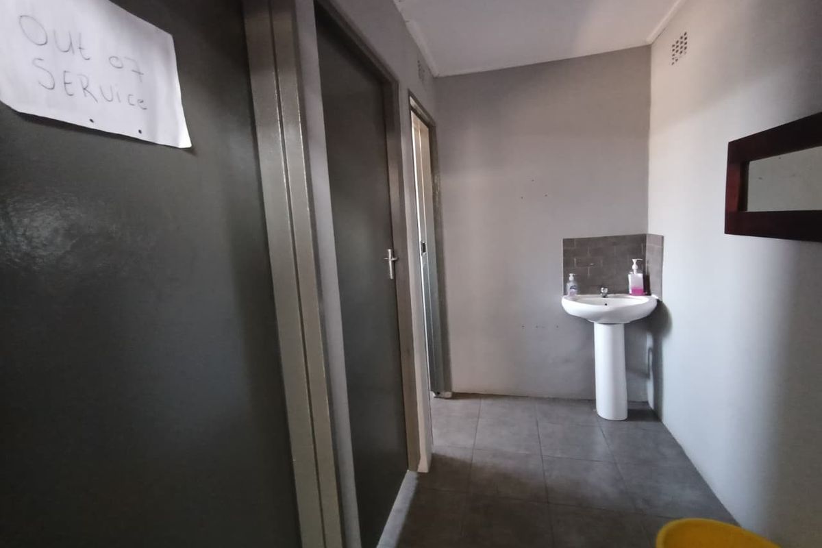 A functional bathroom area featuring a pedestal washbasin and tiled flooring, currently marked as out of service.