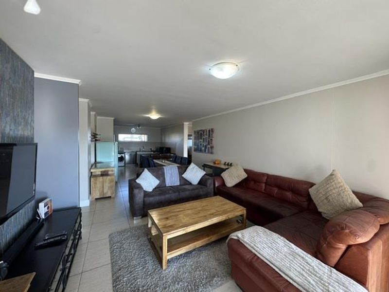 Spacious open-plan living area featuring tiled flooring and a seamless flow into the kitchen space, offering a functional layout for modern apartment living.