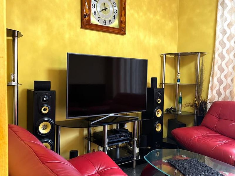 A living room featuring bright yellow textured walls, decorative ceiling molding, and tiled flooring.