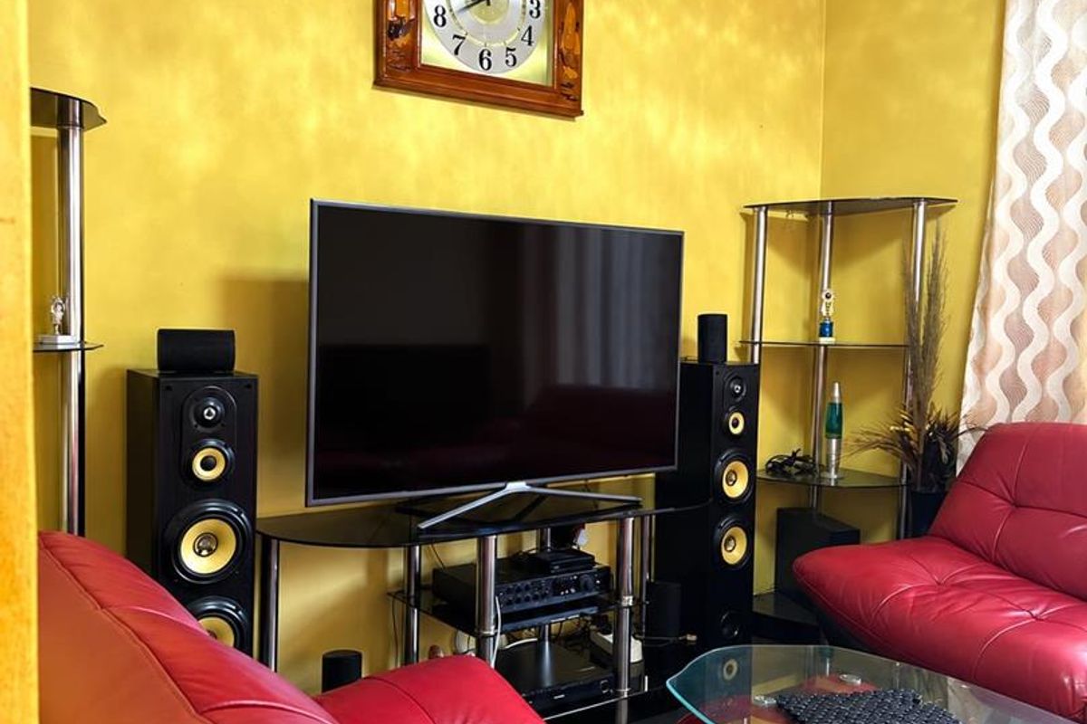 A living room featuring bright yellow textured walls, decorative ceiling molding, and tiled flooring.