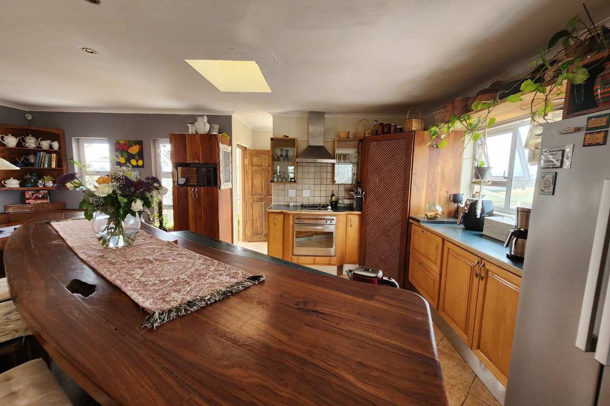 A spacious kitchen featuring wooden cabinetry, a large timber breakfast bar, built-in oven, extractor fan, and a skylight providing natural light.