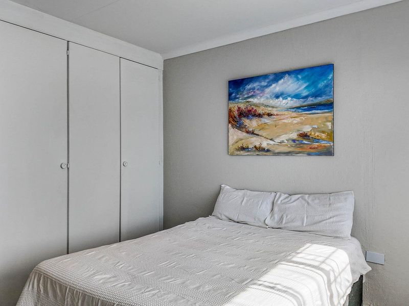 A bedroom featuring built-in cupboards with white doors and neutral wall finishes.