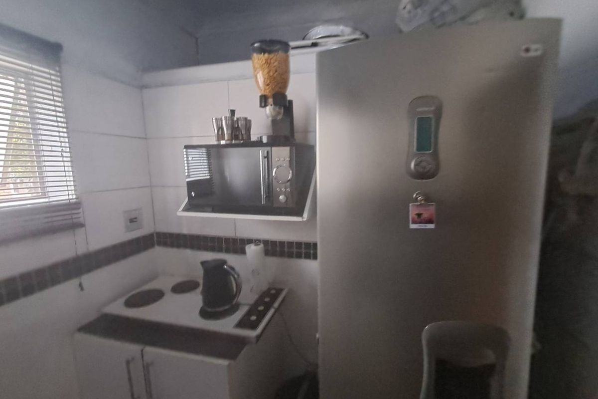 Compact kitchen area featuring built-in cabinetry, tiled splashback, and integrated cooking surface, suitable for a small apartment layout.