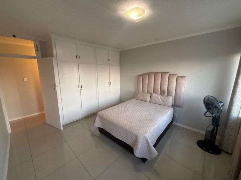 A well-maintained bedroom featuring neutral tiled flooring and ample built-in cupboard storage space.