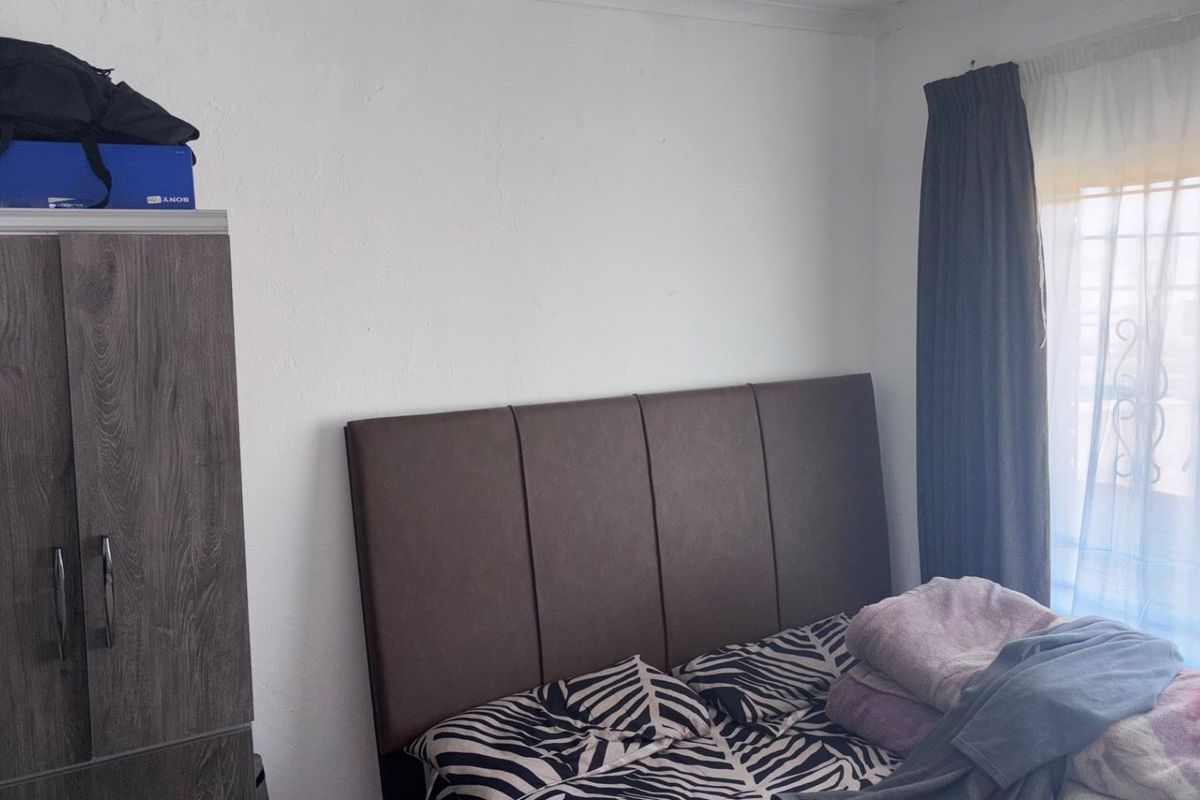 A bedroom featuring a window with curtains and a built-in wardrobe.