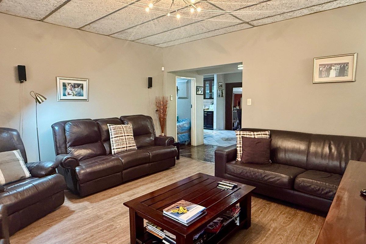 A spacious living room featuring wood-look flooring and a view through to the kitchen area.