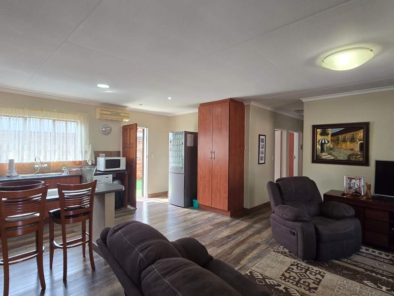 Open-plan living area featuring a functional kitchen with cabinetry, laminate flooring, and integrated air conditioning, creating a cohesive and practical living space.