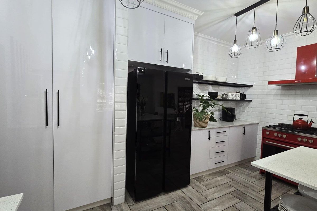 Modern kitchen featuring white cabinetry, subway tile backsplash, stone countertops, herringbone flooring, and a striking red gas stove with matching extractor fan.