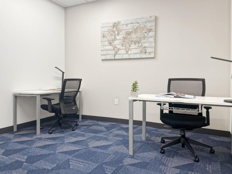 A clean, professional office space featuring patterned carpet tiles and neutral wall finishes, suitable for a productive work environment.