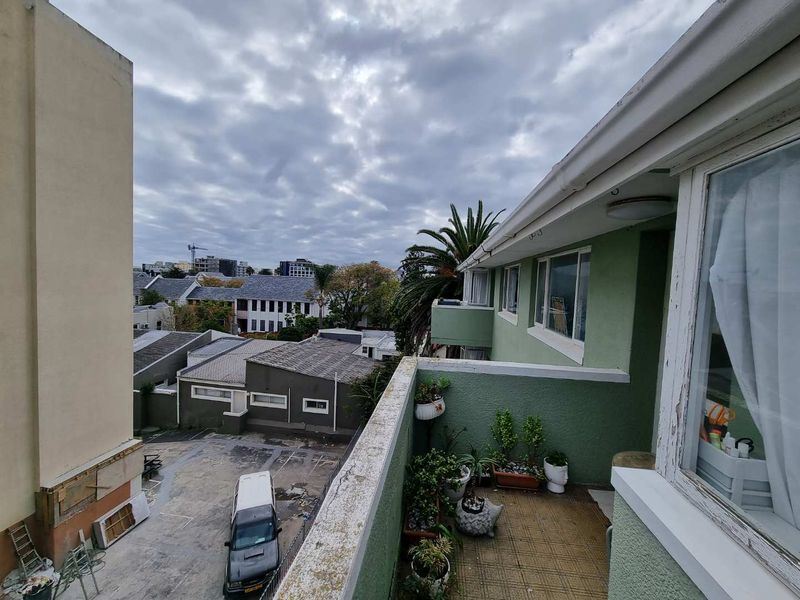 An elevated balcony area with tiled flooring and exterior wall finishes, overlooking the surrounding neighborhood and parking area.